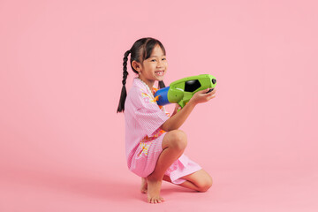 Songkran festival excitement full body as a happy child in a floral outfit sits with a toy water gun © sorapop