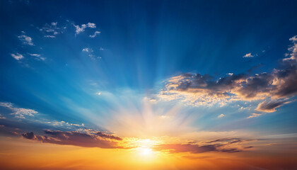 Sunset with sun and clouds on blue and orange sky with sun rays