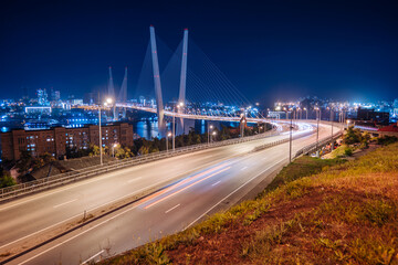 Fototapeta premium Light trails from cars driving across the bridge over zolotoy rog bay in vladivostok, russia, at night