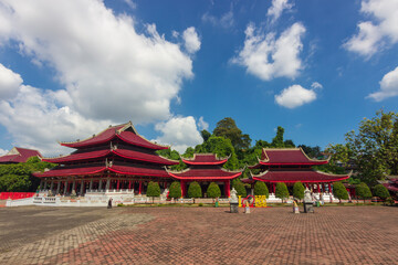 View of the majestic Sam Poo Kong, a beautiful temple complex in Semarang, Indonesia. The temple buildings with their vibrant red tiered roofs dominate the scene, surrounded by lush green trees.