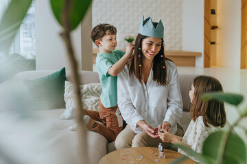 Mother and children playing with a crown toy at home