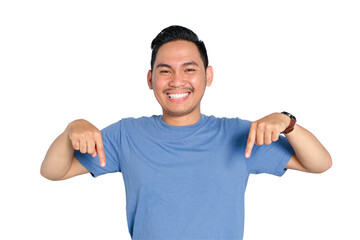 Fototapeta premium Happy young Asian man smiling and pointing downward with both hands, wearing casual blue t-shirt, isolated on transparent background