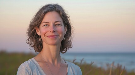 Smiling woman with curly hair by the beach at sunset