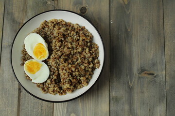 boiled buckwheat and two halves of an egg with a bright yolk in a bowl on a gray background with space for the text of the Space vid Serhu