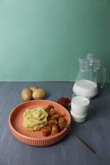 dinner, lunch, tomato sausages with a side dish, potatoes on a plate, a glass of milk, a jug of milk, a place for text, copyspace. The concept of home nutrition
