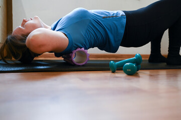 
Woman doing exercises lying on roller at home. Strengthens muscles. Girl doing gymnastics with...