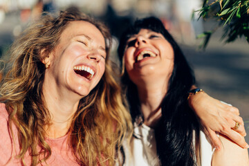 Two happy women laughing together outdoors in the city