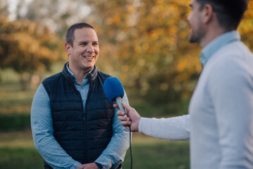 Journalist interviewing smiling farmer in orchard