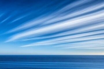 Obraz premium Expansive blue ocean under a clear sky with fluffy white clouds creating a picturesque scene