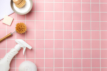 White spray bottle, cleaning brush and sponge on pink tile. Flat lay cleaning products. Cleaner...