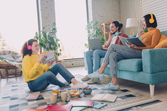 Friends enjoying leisure time together with technology and books in a cozy living room setting