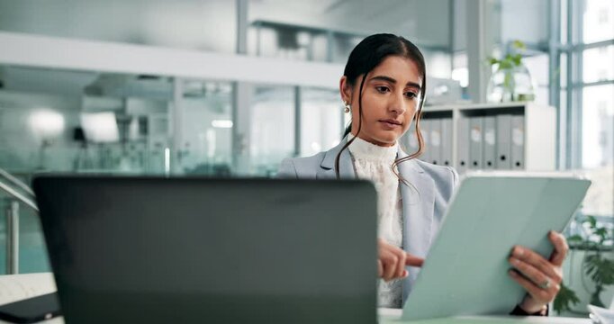 Laptop, tablet and review with business woman at desk in office for administration or research. Computer, information and reading with Indian employee in workplace for online feedback or report