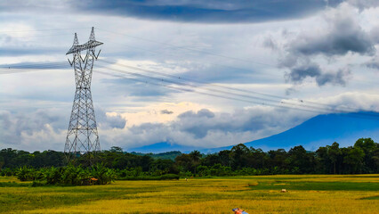 electric tower with mountain background with very dramatic clouds and blue sky