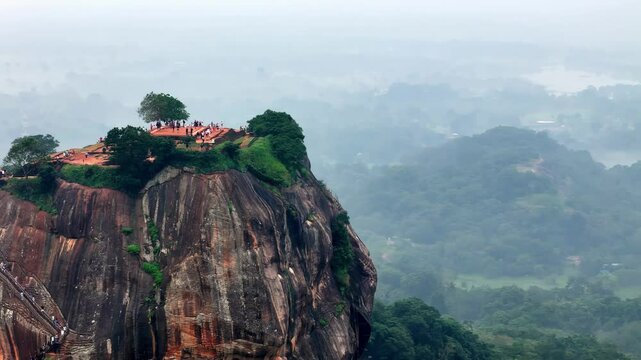 Mist-Kissed Parunthumpara Distant aerial view capturing the rain-soaked rock peak from a helicopter, revealing its rugged cliffs, lush greenery, and tiny figures, wide-angle lens, grey monsoon skies