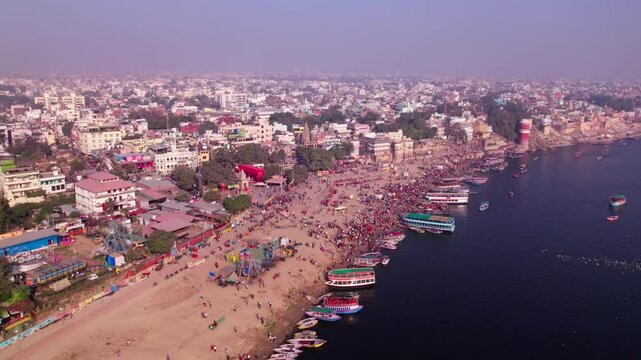 mela with tourist boats are parked on ganga river port and varanasi city at kashi, banaras, uttar pradesh, india. day time, pan shot, drone shot, 4k.