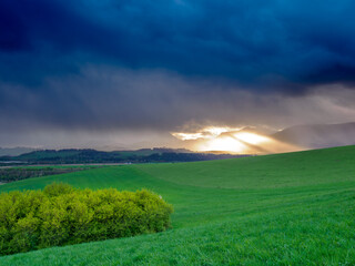 Mountain landscape. A view of the green hills with storm clouds looming over them. You can see the approaching rain from the clouds