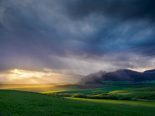 Mountain landscape. A view of the green hills with storm clouds looming over them. You can see the approaching rain from the clouds
