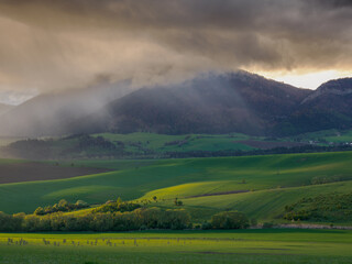 Mountain landscape. A view of the green hills with storm clouds looming over them. You can see the approaching rain from the clouds