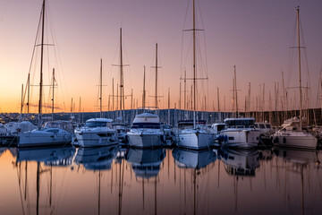 Boats and yachts moored in the harbor lined up with calm water and reflection while a beautiful...