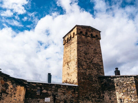 Scene of Lamaria church, old exterior buildings on hill near the Ushguli, UNESCO heritage village on blue sky and cloud background, tourist attraction in the Svaneti region, Georgia.