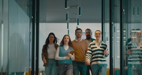 Business team in a modern open space startup office walking together. Diverse group of businesspeople smiling while having a discussion. Successful mixed race colleagues collaborating on a new project