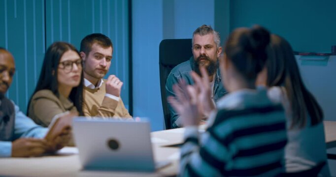 A diverse team of young professionals collaborates in a modern office conference room. Businesspeople discuss strategy, technology, and planning, using laptops to develop an innovative e-commerce