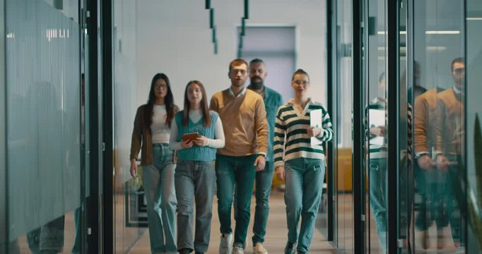 Business team in a modern open space startup office walking together. Diverse group of businesspeople smiling while having a discussion. Successful mixed race colleagues collaborating on a new project