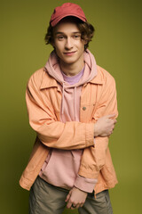 Young man showcases modern fashion in a playful studio setting with energetic green backdrop