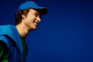 Young man showcases modern fashion style against vivid blue backdrop in lively atmosphere