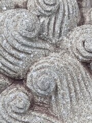 a close-up of a stone carving with a spiral pattern. The carving is made of gray stone and has a...