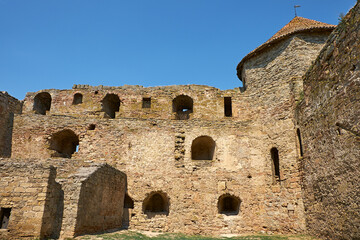 Ancient medieval fortress with massive stone towers near the sea under a clear blue sky.