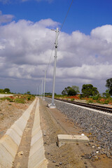 Fototapeta premium Railway View Stretching Across Green Fields Under a Cloudy Sky