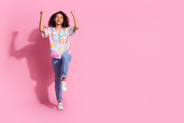 Joyful young woman expressing positivity against a vibrant pink background with casual trendy style