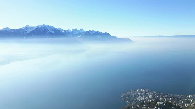 Aerial: landscape from Caux Palace Hotel of Lake Geneva and Alps mountain range in canton of Vaud, Switzerland, establishing drone shot