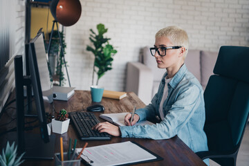 Casual professional woman working on computer at her home office in the daylight