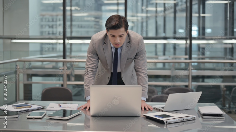 Poster businessman working on a laptop computer in an office setting. he appears focused on the screen.