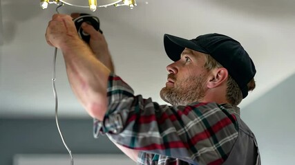A skilled electrician works on installing a ceiling light fixture in a well-lit living room, ensuring proper wiring and functionality for the home.