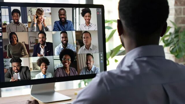 A group of professionals participates in a lively virtual meeting, sharing insights and collaborating on various topics across a large computer screen in a bright office.