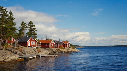 Obraz premium Wooden cabins on the shores of a lake, with boats at the dock.