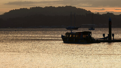 Scenic Sunset at the Marina with Boat Docked on Calm Waters and Mountain Silhouette in the Background