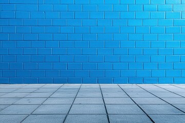 Fototapeta premium Big vivid blue brick wall extends along street sidewalk. Empty urban scene offers copy space. Horizontal photo captures large brick wall in city. Street background perfect for creative