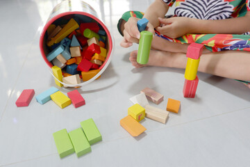 A boy's hands are playing with colorful wooden building blocks.