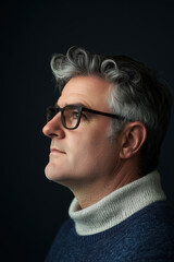 Fototapeta premium Profile Portrait of Middle-Aged Man with Gray Hair and Glasses Against Dark Background