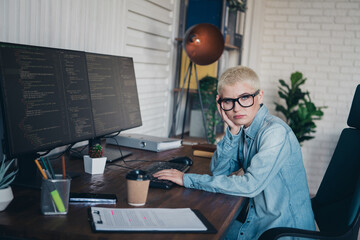 Young female programmer working in a home office with computers and coding software