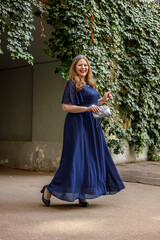 Woman in a long blue dress in the garden.