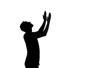 The silhouette of the back of a child praying with his hands held high