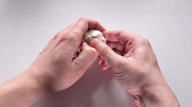 Two Hands Peeling Garlic. Cooking Ingredient Preparation. Peeling Garlic Cloves by Hand. Food Preparation Process.
