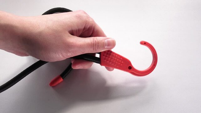 Hand Holding Bungee Cord with Hook. Close-up of Hand with Bungee Cord