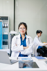 Confident young male doctor in white medical uniform sit at desk working on computer. Smiling use laptop