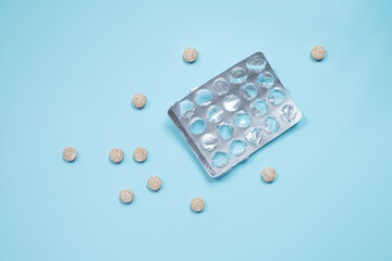 Empty blister pack and pills on blue background